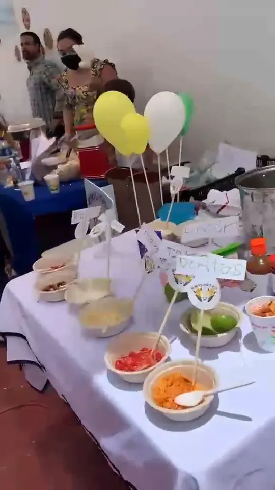 Mesa del puesto con bowls de toppings, globos y etiquetas en el Business Fair